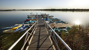 Une jetée menant à un quai où sont amarrés des kayaks et des canoës.