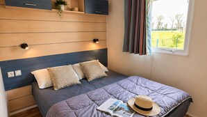 Una camera da letto con un letto, una finestra con tende, un comodino con una pianta e una mensola a muro.