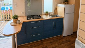 Una cucina compatta con piano cottura a gas, lavello e frigorifero integrato.