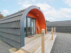 A modern building with a curved entrance, a wooden deck, and a metal roof.