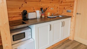 Una cocina compacta con paredes de madera, microondas, tostadora y pileta.