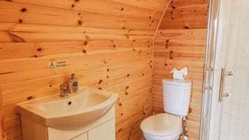 A wooden cabin bathroom with a sink, toilet, and shower.