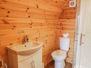 Een houten badkamer in een vakantiehuis, met een wastafel, toilet en douche.