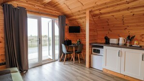 Un interior de madera con comedor, cocina y puertas corredizas de vidrio que dan a un espacio exterior.