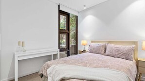 Ein Schlafzimmer mit einem Bett, Nachttischen, einem Schreibtisch und einem Fenster.