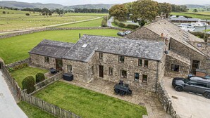A stone building with a patio, a car, and a view of the countryside. - Orcaber Farm Retreat (Lancaster)