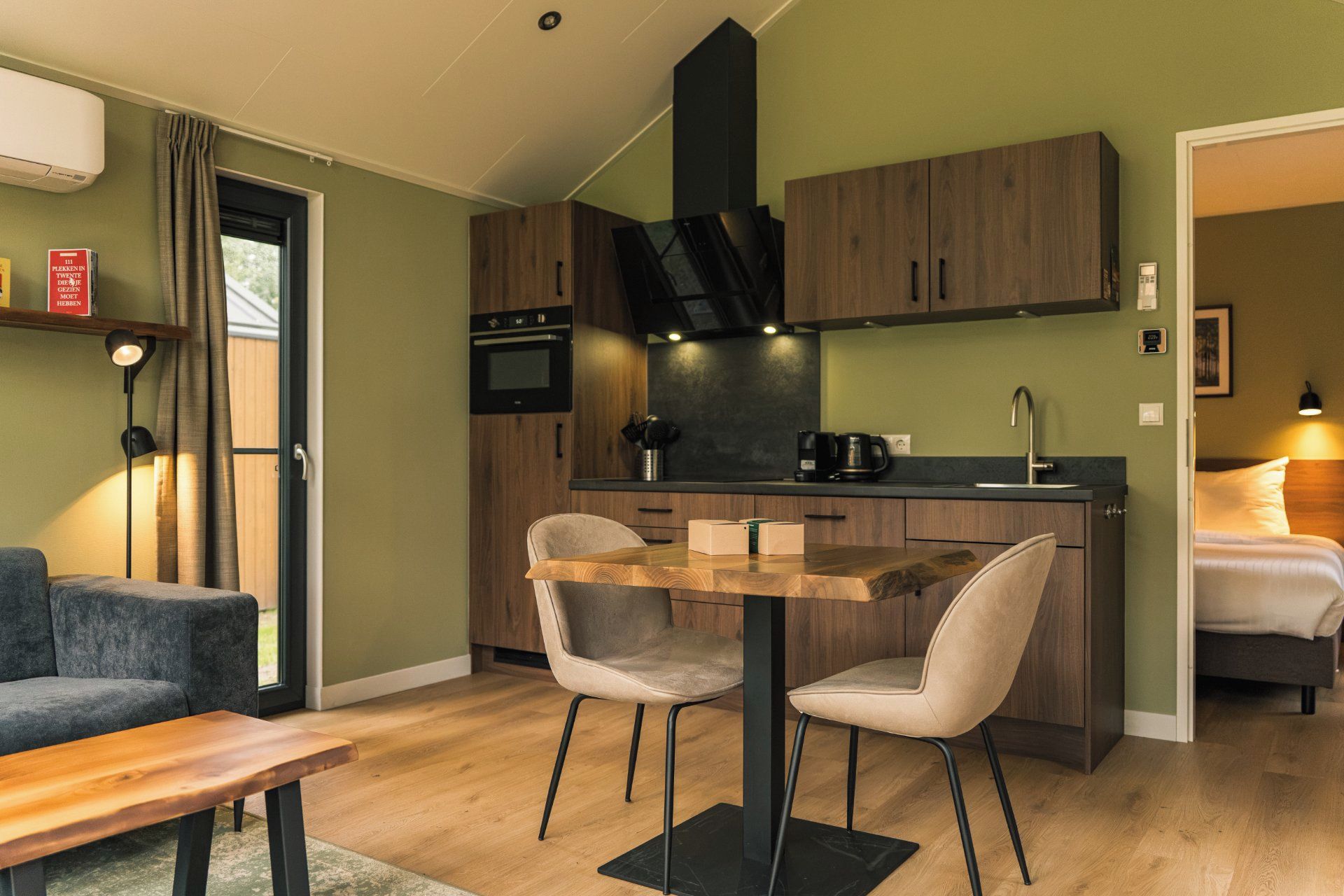 A compact living space with a kitchenette, a dining area with two chairs, a sofa, and a bed.