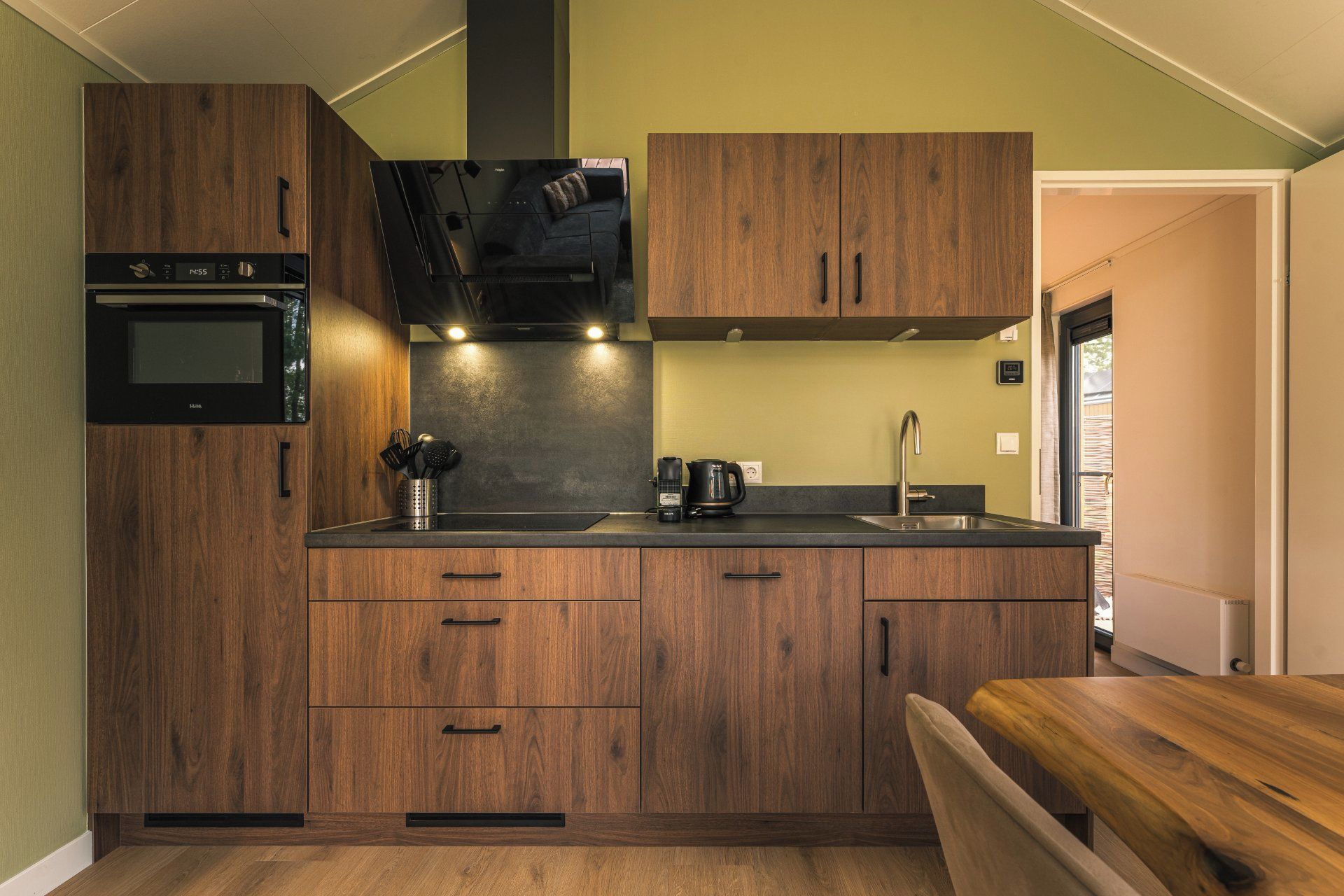 A compact kitchen with wooden cabinets, a built-in oven, and a coffee maker.