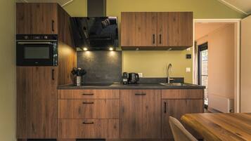 A compact kitchen with wooden cabinets, a built-in oven, and a coffee maker.