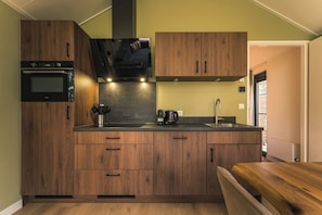 A compact kitchen with wooden cabinets, a built-in oven, and a coffee maker. - Enjoy a romantic stay in the Forest Lodge with sauna for 2 people. A luxury villa in nature with a terrace, rain shower and comfortable box spring bed. (Lattrop-Breklenkamp)