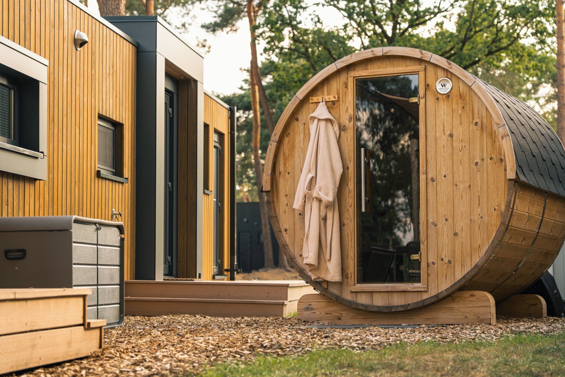 A wooden barrel-shaped structure with a door and a towel hanging on the inside.