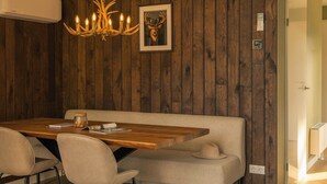 Uma sala de jantar com uma mesa de madeira, cadeiras, um banco, um candelabro e um quadro na parede.