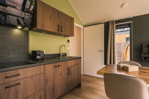 A modern kitchen with wooden cabinets, a black countertop, and a coffee maker. - Luxury Forest Lodge with hot tub and sauna for 2 people. Enjoy peace, nature and comfort with private wellness, a terrace and a modern kitchen. (Lattrop-Breklenkamp)