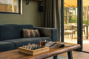 A living room with a sofa, a coffee table, and a chess set. - Luxury Forest Lodge with hot tub and sauna for 2 people. Enjoy peace, nature and comfort with private wellness, a terrace and a modern kitchen. (Lattrop-Breklenkamp)