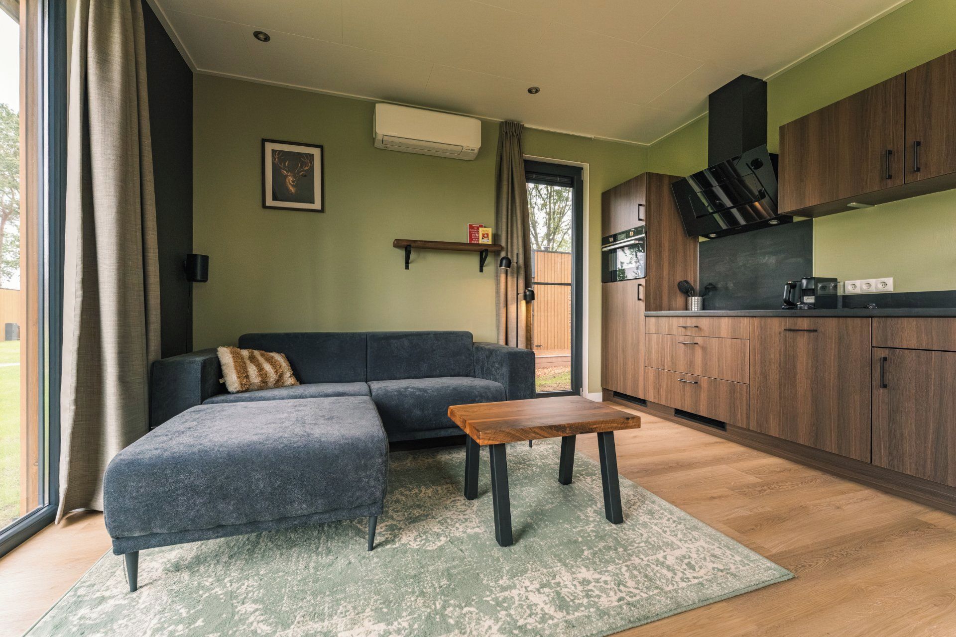 Un salon moderne avec un canapé d’angle, une table basse et une vue sur une terrasse, accessible par une porte vitrée.