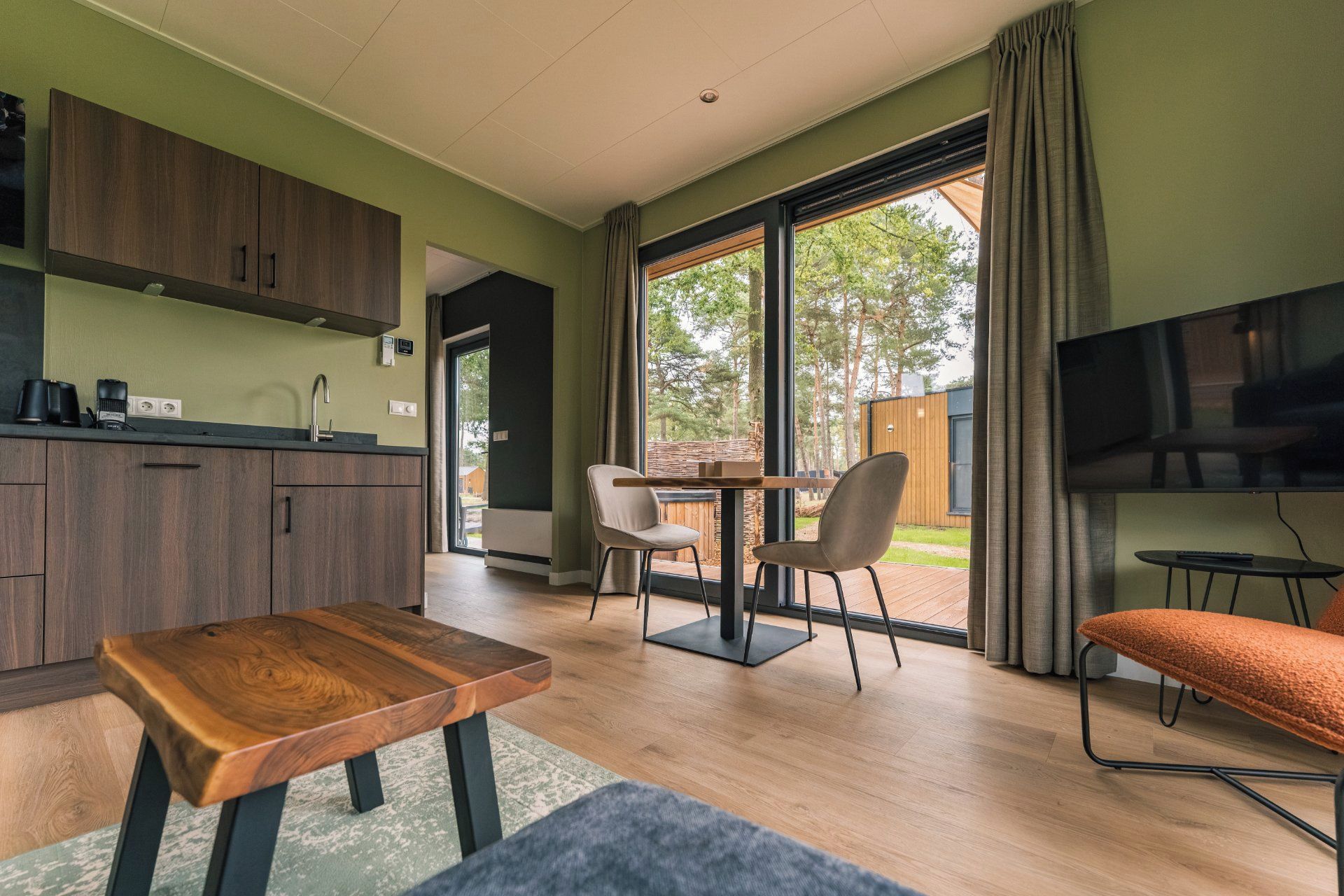 A modern kitchen with a dining area, a television, and a view of the outdoors.