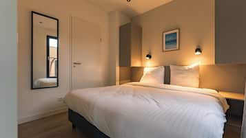 Een slaapkamer met een bed, nachtlampen, een spiegel en een schilderij aan de muur.