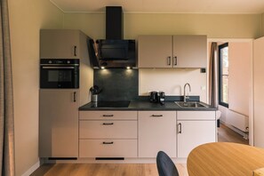 A compact kitchen with a built-in oven, a coffee maker, and a sink.