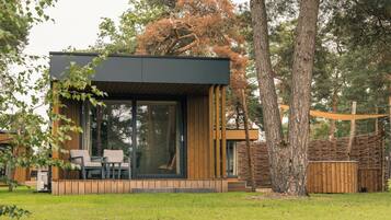 A modern outdoor living space with a glass enclosure, wooden deck, and seating area.