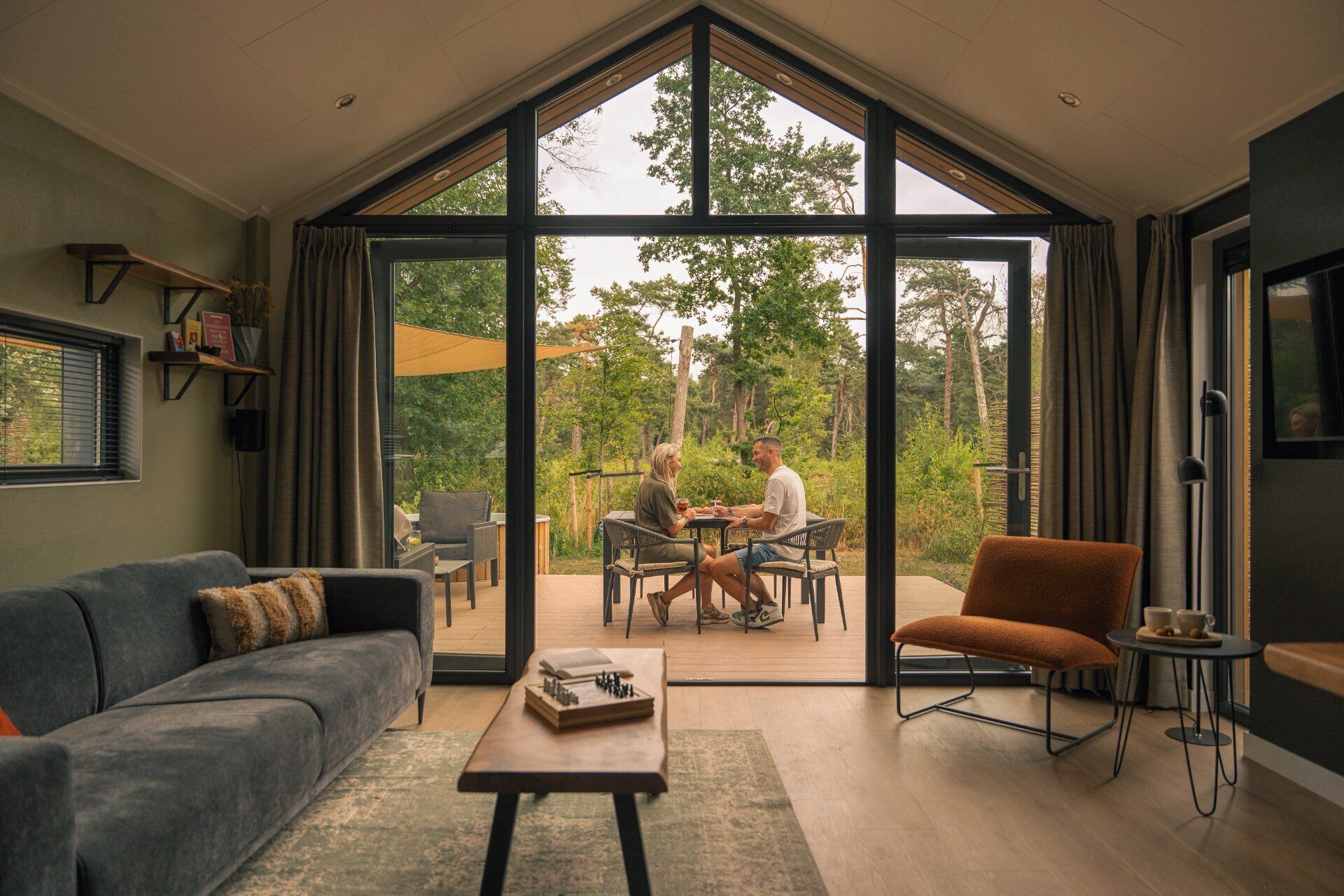 Een ruime woonkamer met een grote glazen deur die leidt naar een terras.