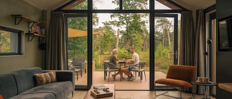 Uma sala de estar espaçosa com uma grande porta de vidro que dá para uma área externa com assentos.
