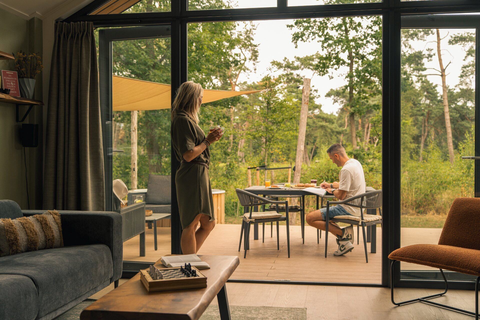 Een modern interieur met een grote glazen deur naar een buiten eethoek.