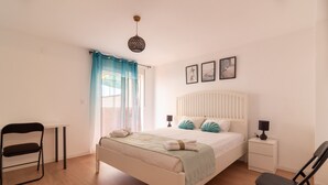 Ein Schlafzimmer mit Bett, Stuhl, Nachttisch, kleiner Tisch und Lampe.
