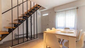 Ein modernes Interieur mit Treppe, Esstisch, Stühlen und einem fenster mit Vorhängen.