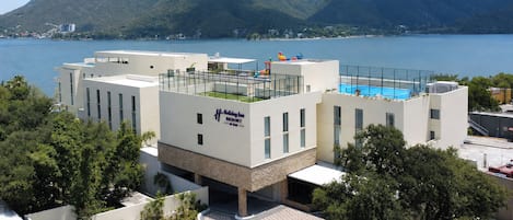 A modern Holiday Inn Resort with a rooftop pool, surrounded by mountains and a lake.