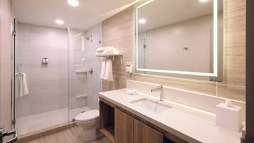 A modern bathroom with a glass shower enclosure, a toilet, a vanity with a sink, and a large mirror.