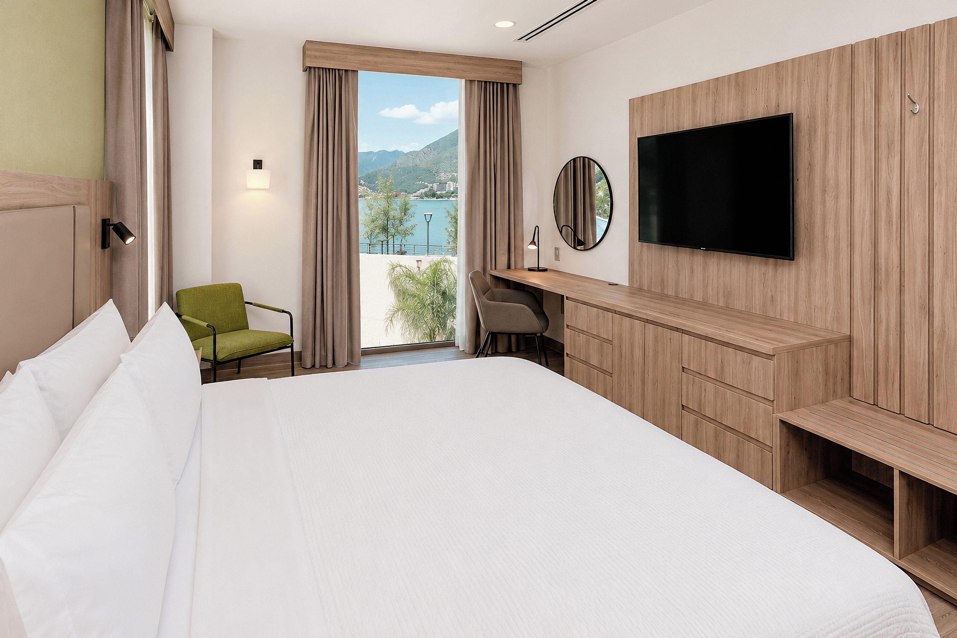 A hotel room with a large bed, a desk with a chair, a TV, and a view of the outdoors.