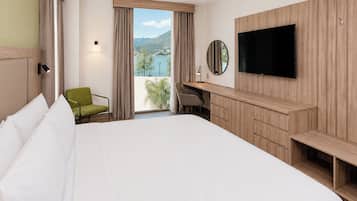 A hotel room with a large bed, a desk with a chair, a TV, and a view of the outdoors.