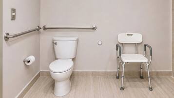 A bathroom with a toilet, a handrail, and a mobility aid.