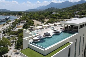 Una piscina infinita en la azotea con vistas al mar y a las montañas.