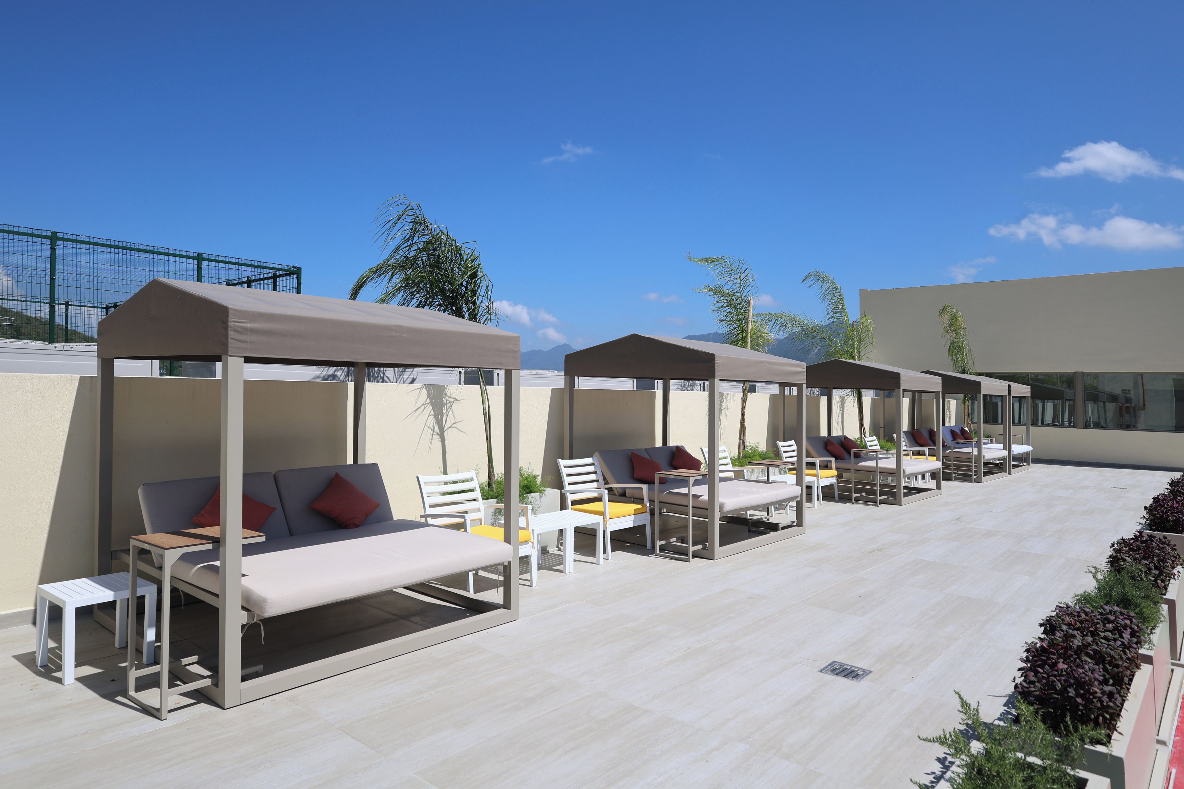 Terraza en la azotea con zonas de estar al aire libre, que incluyen tumbonas y mesas, bajo toldos.