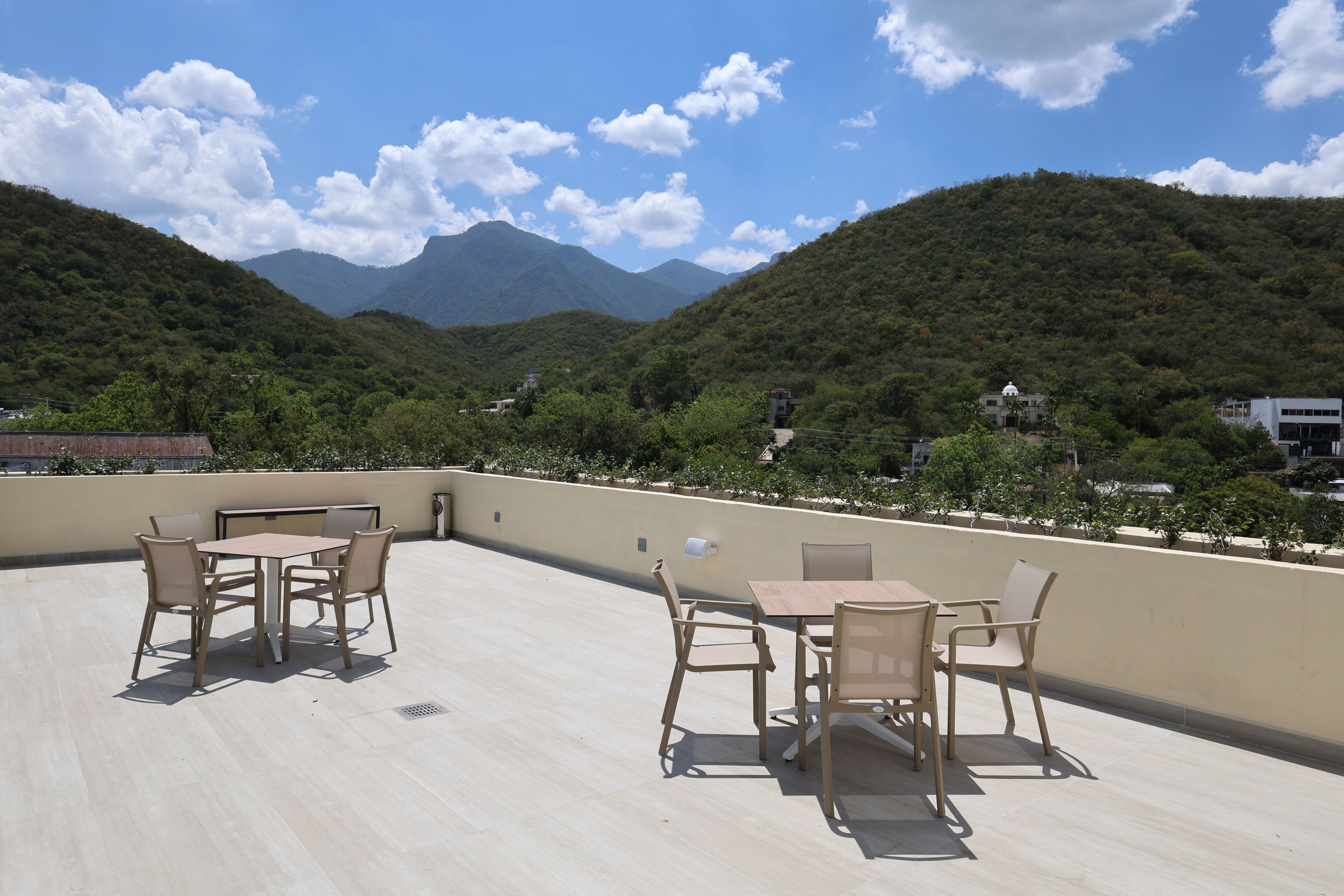 Une terrasse sur le toit, avec une table et des chaises, d’où l’on peut admirer un paysage montagneux.