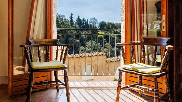 A balcony with two wooden chairs, a view of greenery, and a tiled floor. - Moulin St Jean - Nature in the heart of the village (Tourrettes-sur-Loup)