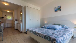 Una camera da letto con un letto, un comodino e vista sulla cucina.