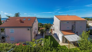 Una zona residenziale con due edifici, uno con tetto in tegole rosse e l'altro con facciata bianca.