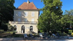 A large stone building with a swimming pool, outdoor seating, and lush greenery. - Château de Foussal (Plaisance)