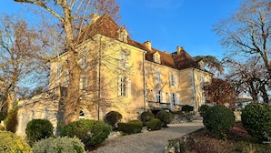 A large, historic building with a symmetrical facade, multiple chimneys, and a gravel driveway leading to a stone staircase. - Château de Foussal (Plaisance)