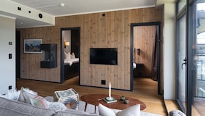 A modern living room with a wooden wall panel, a flat-screen TV, a cozy sofa, and a coffee table. - New (2023) apartment with very central location. (Hol)