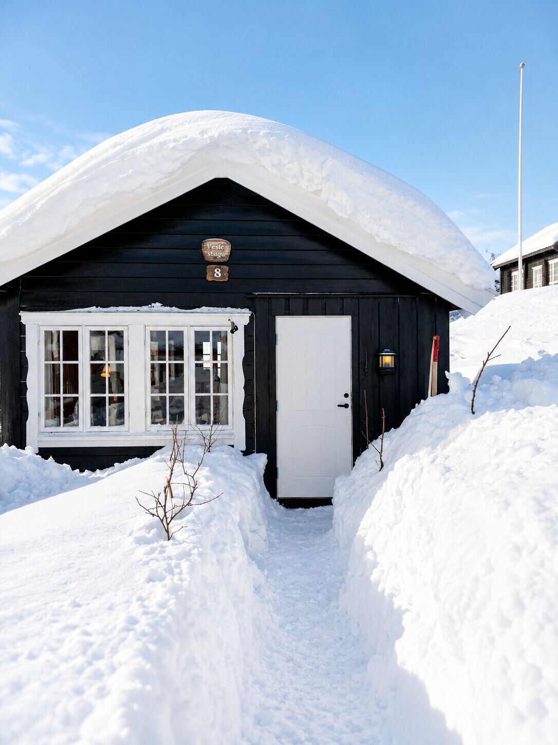 Une cabane en bois recouverte de neige, avec une porte blanche, des fenêtres et une enseigne indiquant le numéro 8.