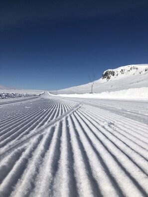 A snow-covered road with tire tracks leading towards a mountain.