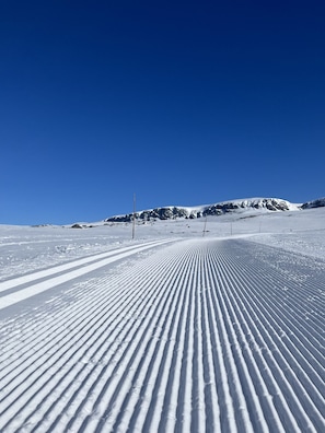 A snowy ski slope with a clear blue sky.