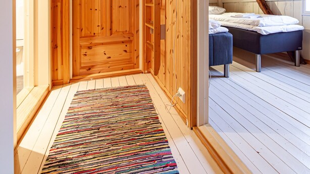 Un interior de madera con una puerta, una cama y una alfombra colorida.