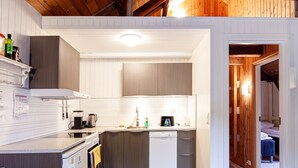 Una cocina compacta con vigas de madera, muebles blancos y un pequeño comedor.