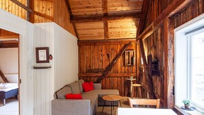 Un interior de madera con sofá, mesa, sillas, una ventana y una puerta que da a otra habitación.