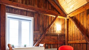Un interior de madera con una mesa de comedor, sillas, una butaca roja y un radiador.
