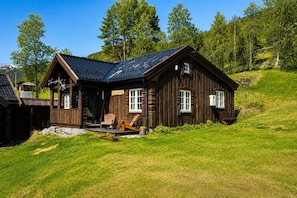 Eine Holzhütte mit Veranda, zwei Fenstern und einem Schornstein.